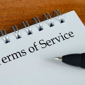 Terms of Service text on white notepad with wooden table background. Terms of Service concept.